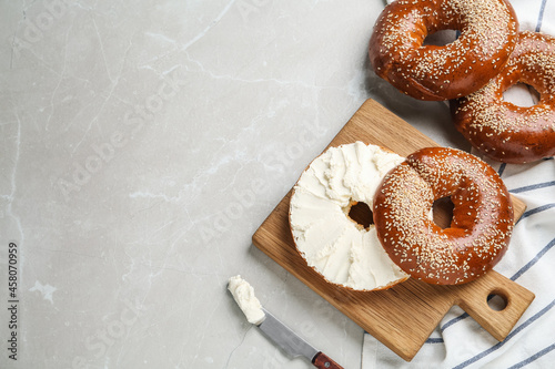 Delicious bagel with cream cheese on light table, flat lay. Space for text photo