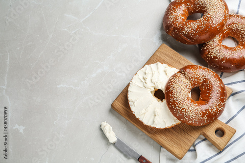 Tableau sur toile Delicious bagel with cream cheese on light table, flat lay