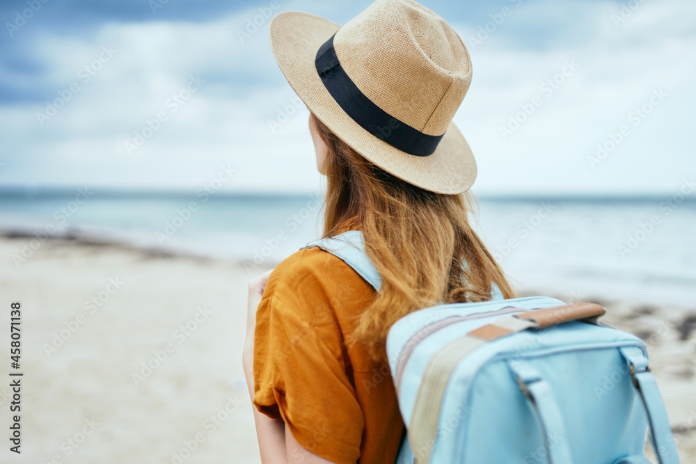 woman tourist with backpack travels on the beach island fresh air