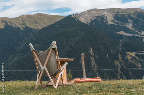 Silla de tela y una mesita delante de un paisaje montañoso photo