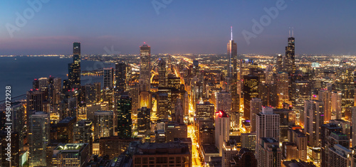 Beautiful panoramic aerial night skyline view at dawn of the city of Chicago with building and street lights on just before sunrise with blue sky and pink clouds on the horizon.