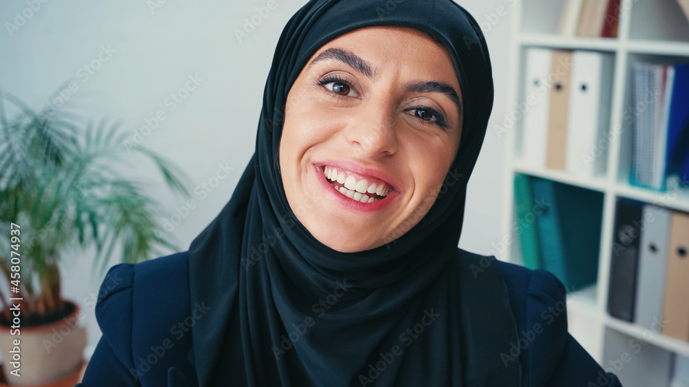 young muslim businesswoman in hijab smiling while looking at camera young muslim businesswoman in hijab smiling while looking at camera