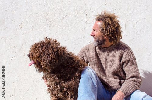 man and dog very similar, they have brown curly hair and both look at the same point