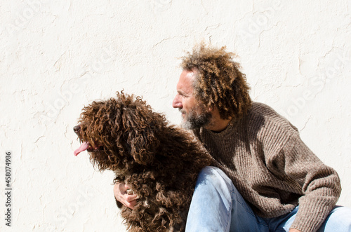 middle-aged man hugs his dog, they are sitting and looking at the same point