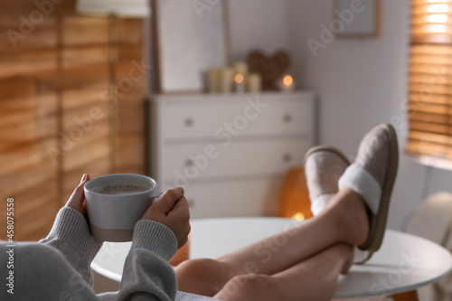 Woman with cup of aromatic coffee relaxing at home, closeup