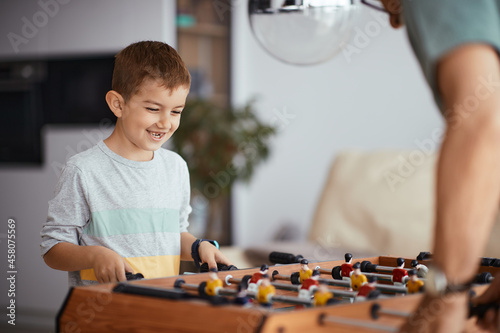 Happy kid plays table football with his grandfather at home. photo