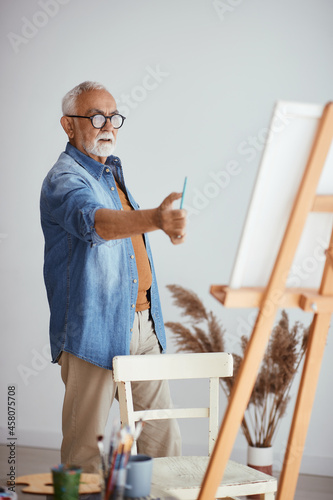 Senior artist uses the rule of thumb while painting at home.