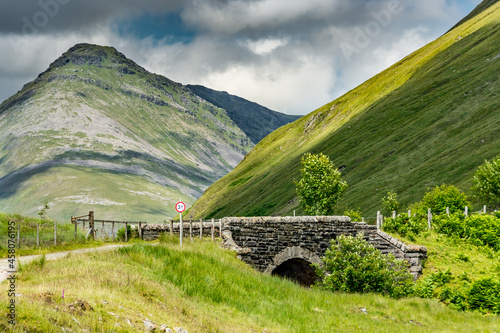 Along the West highland Way in Scotland. An old stone bridge spans the railway track near Beinn Dorain mountain photo
