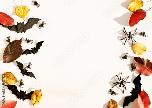 Top view white background with bats  spiders and autumn leaves with copy space for text. Mock up of Halloween holiday concept.