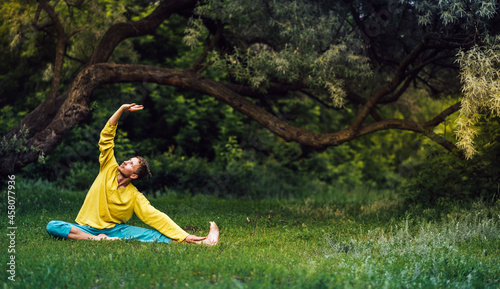 Man doing parivrtta janu sirsasana right exercise. Qigong practice in the park. photo
