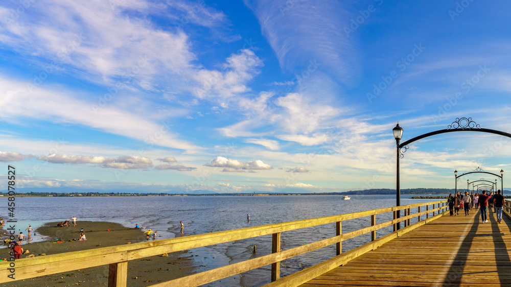 Low tide at Semiahmoo Bay, White Rock, BC, as viewed from a crowded White Rock Pier, Canada's longest, on a sunny late summer Sunday afternoon