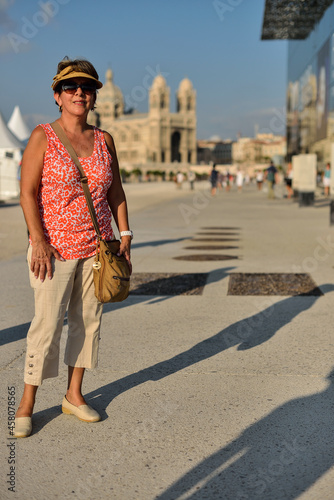 Latin woman tourist posing smiling with the Cathedrale La Major in Marseille at the background. Vacation tourism concept.