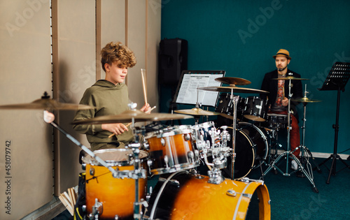 Fotografering The boy plays the drum kit. Music lesson with teacher.