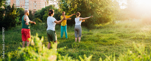 The coach conducts a warm-up. Group learning qigong in nature. photo