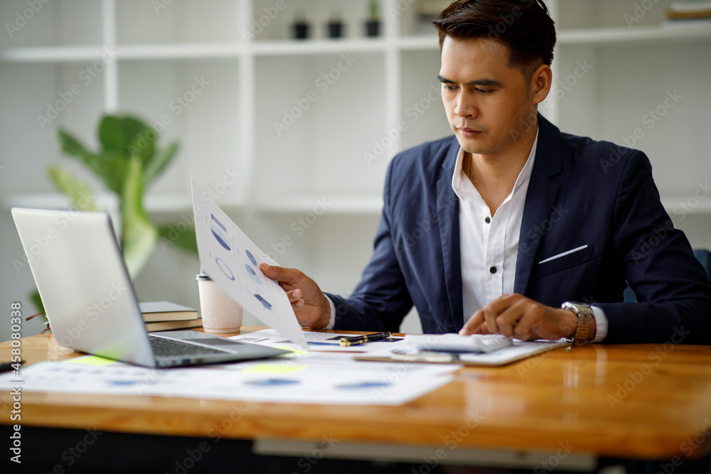 A young handsome man or businessman working on laptop computer in modern office. doing finances, accounting analysis, report data pointing graph Freelance education and technology concept. A young handsome man or businessman working on laptop computer in modern office. doing finances, accounting analysis, report data pointing graph Freelance education and technology concept.