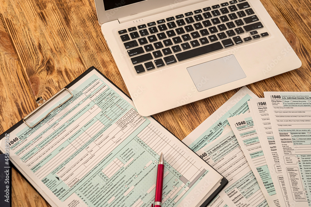 Obraz premium on a wooden table are a laptop, calculator, dollar bills, pen and tax forms