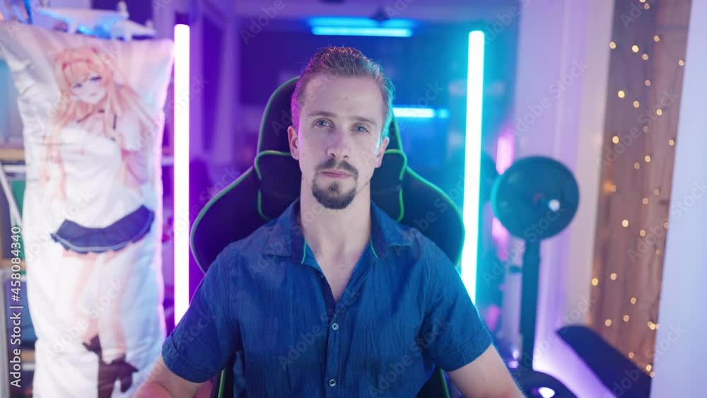 Man on gaming chair looking at camera surrounded with neon lights and anime girl body pillow 4K Man on gaming chair looking at camera surrounded with neon lights and anime girl body pillow 4K