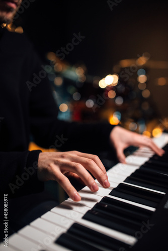 Man playing the synthesizer keyboard close up.