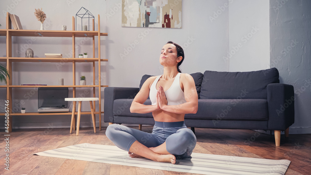 Barefoot sportswoman practicing yoga in living room Barefoot sportswoman practicing yoga in living room