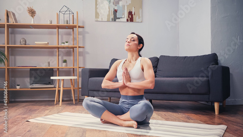 Barefoot sportswoman practicing yoga in living room