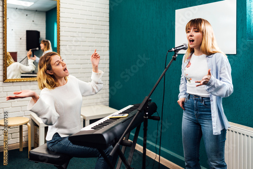 Obraz na plátně Woman singer rehearsing her song on a lesson with a teacher