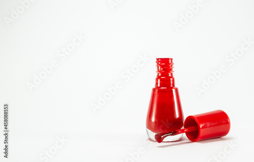 Red nail polish glass bottle, with copy space on white background.