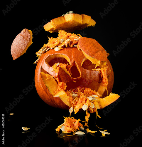 Halloween pumpkin exploding pieces. Decorative Jack-o'-lantern on black background.