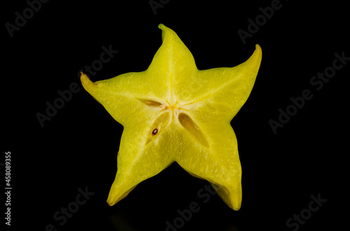 Carambola (star fruit or 5 fingers). Star-shaped slice of fresh and delicious Averrhoa carambola on black background.