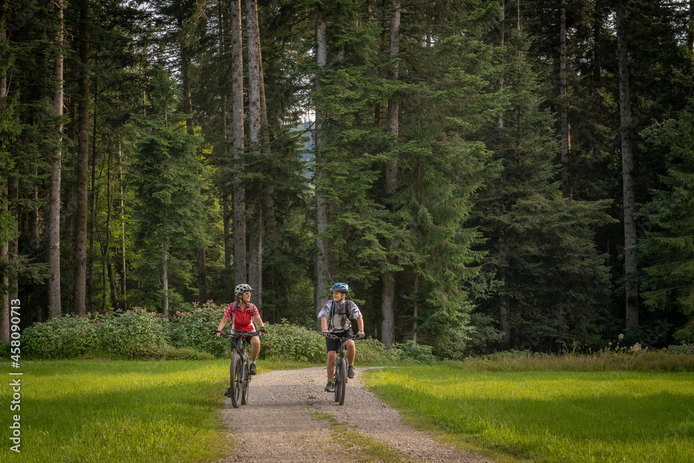 Obraz premium nice and remained young grandmother and her grandson riding their electrc mountain bikes in the Allgaeu Alps near Oberstaufen in Bavaria, Germany