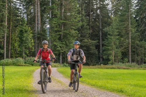 nice and remained young grandmother and her grandson riding their electrc mountain bikes in the Allgaeu Alps near Oberstaufen in Bavaria, Germany