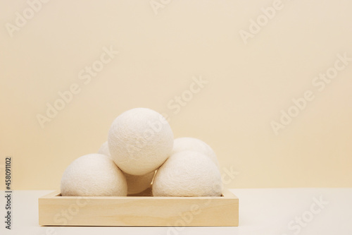 Fototapeta Naklejka Na Ścianę i Meble -  Wool Dryer Balls On Wooden Podium On Beige Background. Eco Friendly Laundry Supplies. Alternative Drying Of Linen. Still Life. Text Space