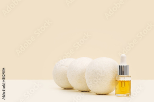 Wool Dryer Balls And Oil Aroma Bottle On Beige Background. Eco Friendly Laundry Supplies. Alternative Drying Of Linen. Still Life. Text Space