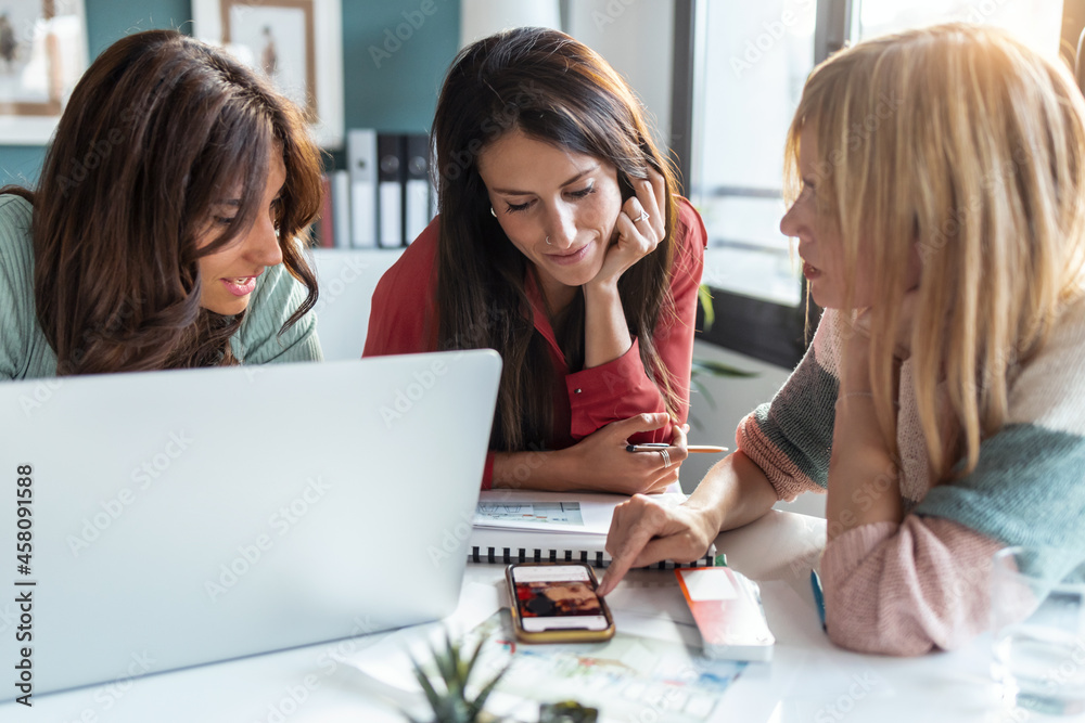 Group of multiage designer women working in a design project while choosing materials in the office. Group of multiage designer women working in a design project while choosing materials in the office.