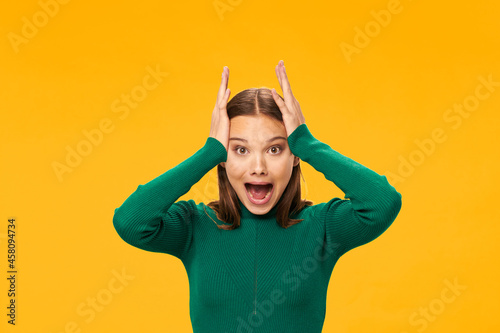 Fotografía woman in green sweater holding her head emotions yellow background model