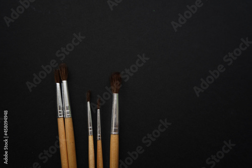 A set of brushes made of pile with a wooden handle on a black background