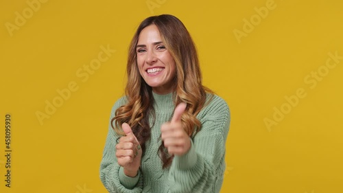 Excited young brunette woman 30s years old wears mint sweater point index finger camera on you motivating encourage showing thumb up like gesture isolated on plain yellow background studio portrait