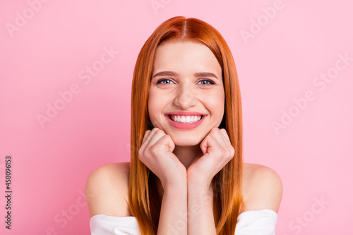 Photo of positive pretty young redhead woman hold fists good mood smile isolated on pastel pink color background