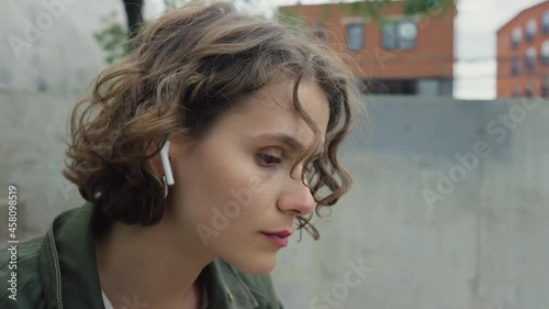 Young beautiful candid woman put wireless earphones in to enjoy soft rhythmical beats