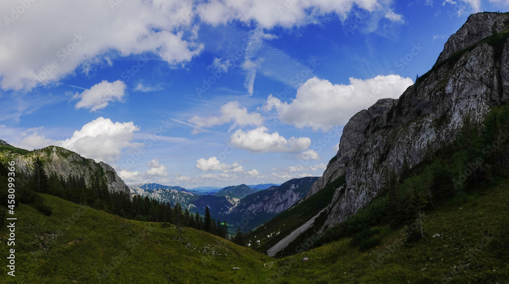 view to a deep valley with mountains and white clouds on the blue sky panorama