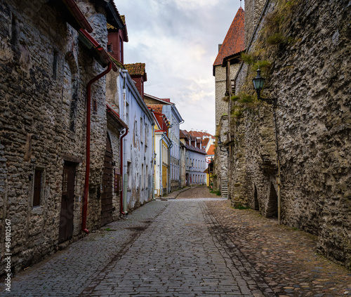 Cobbled alley with medieval houses and stone wall in Tallinn Estonia.