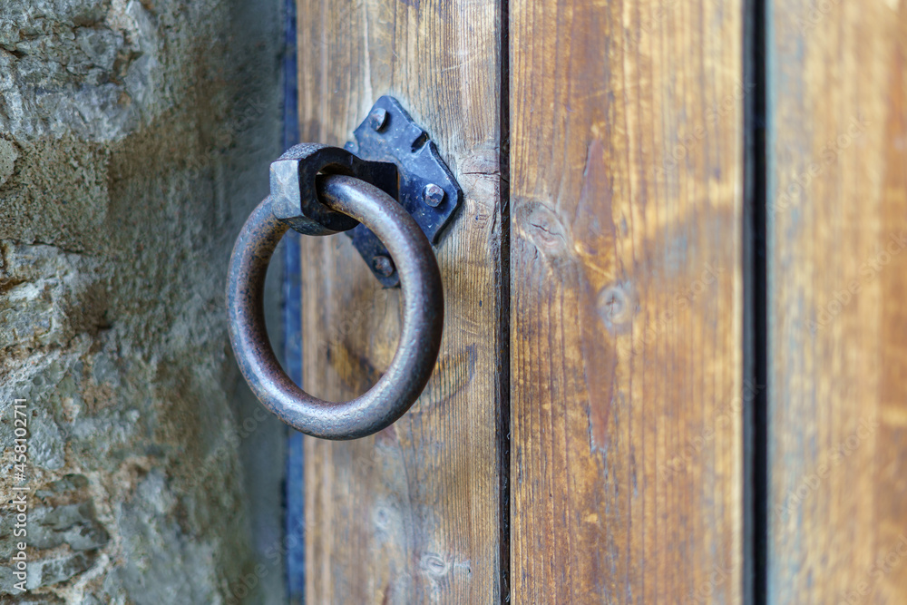 Detail of metal knocker on wooden door in medieval style.