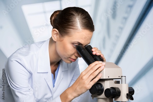 Scientist woman doctor analyzing test results using medical microscope