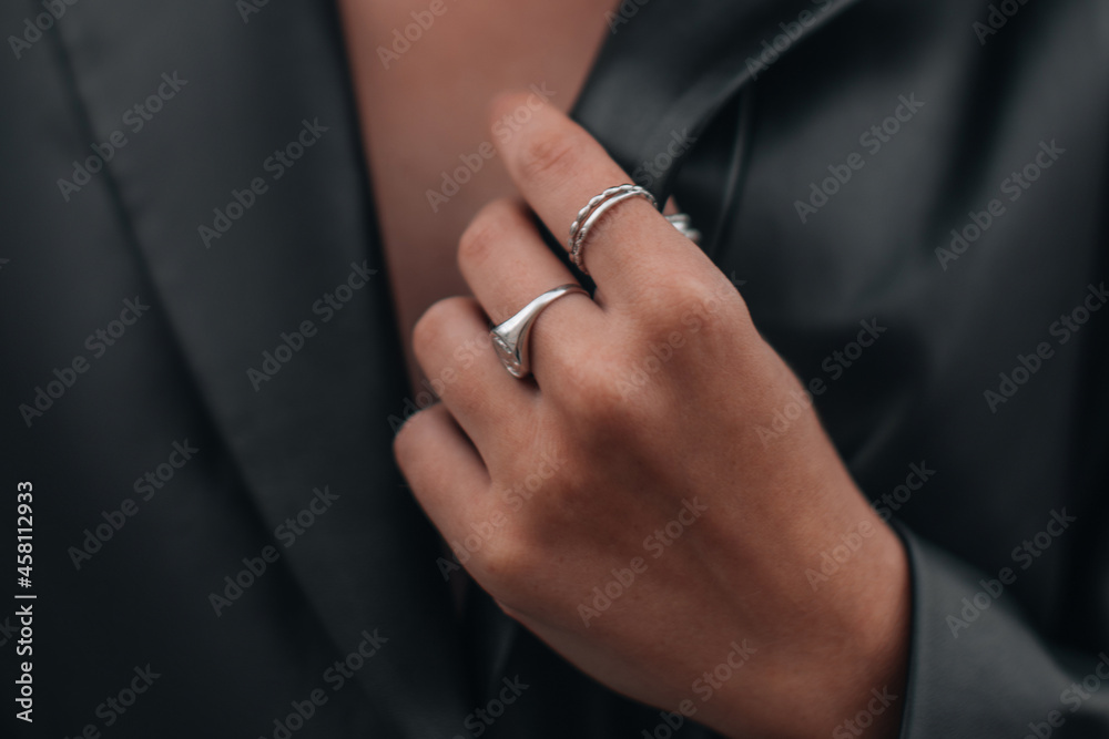 Female hands in a black stylish leather jacket and silver accessories on a female body. Jewelry and women's fashion.