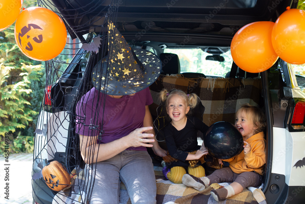 Naklejka premium Father two kids celebrating Halloween in car trunk. Autumn holiday