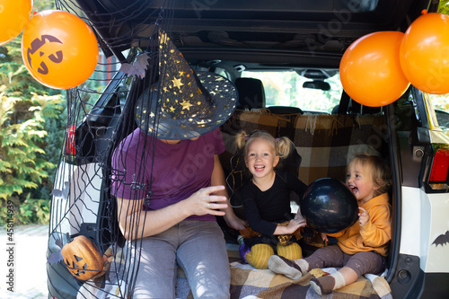 Father two kids celebrating Halloween in car trunk. Autumn holiday