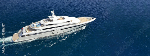 Aerial drone ultra wide panoramic photo of beautiful modern super yacht with wooden deck cruising in high speed deep blue open ocean sea photo