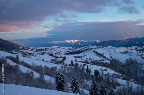 Winter sunset in the mountains. Snow-covered mountain range, illuminated by the setting sun..