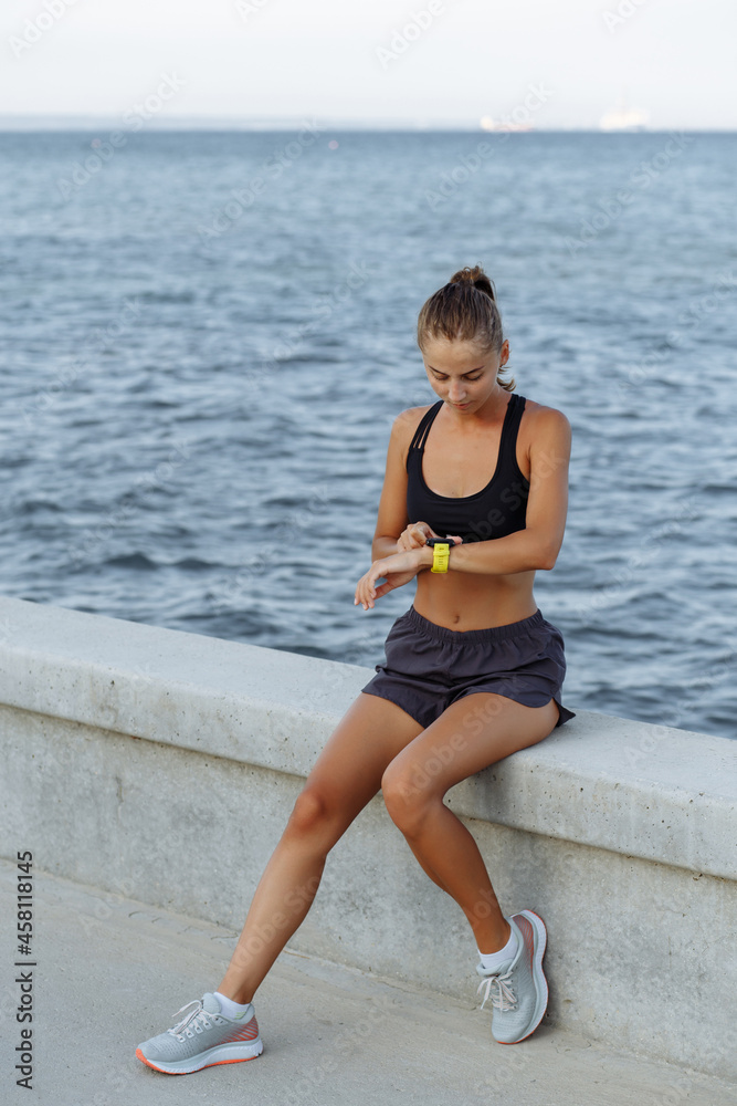 beautiful fitness girl with a sports watch sitting by the sea beautiful fitness girl with a sports watch sitting by the sea