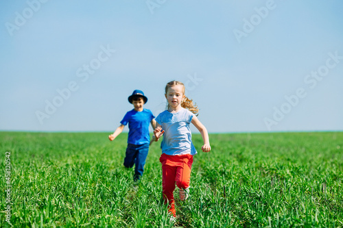 Running kids in green field during summer.