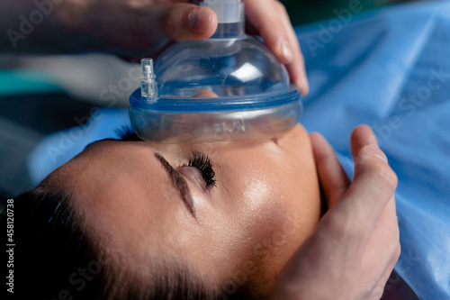 Anesthesiologist making ingalation anesthesia for patient. Doctor puts a mask on the patient before starting operation photo